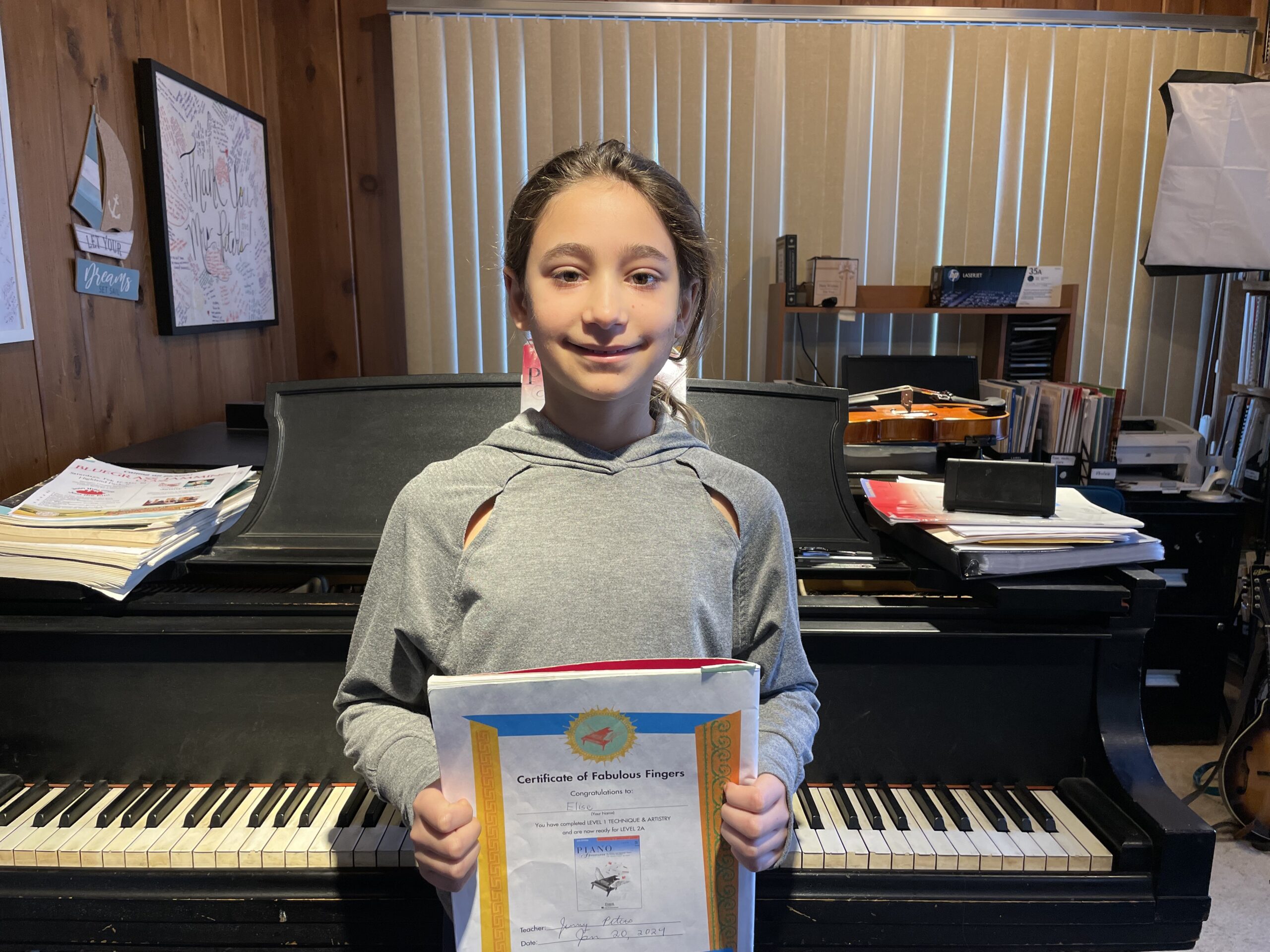 Girl holding certificate in front of piano